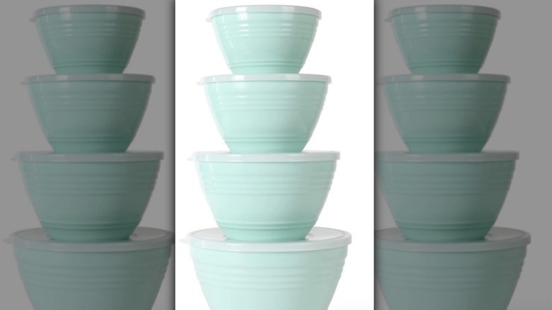 Stack of mixing bowls with lids on white background