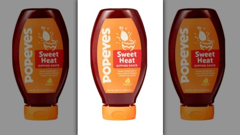 Popeyes sweet heat sauce with an orange label and lid on white background