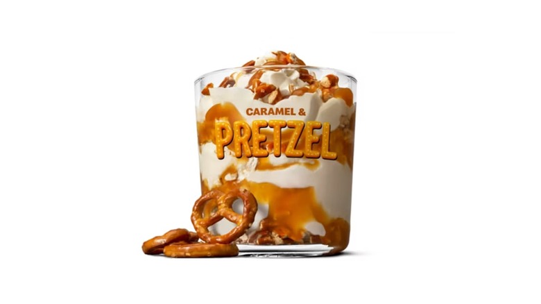 A cup reading caramel and pretzel full of ice cream with caramel and pretzels