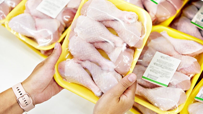 person holding package of raw chicken