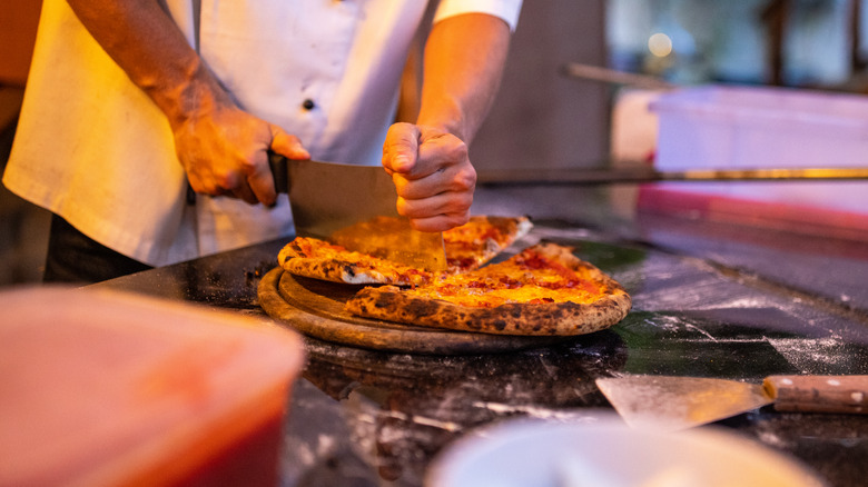 chef slicing pizza with cleaver
