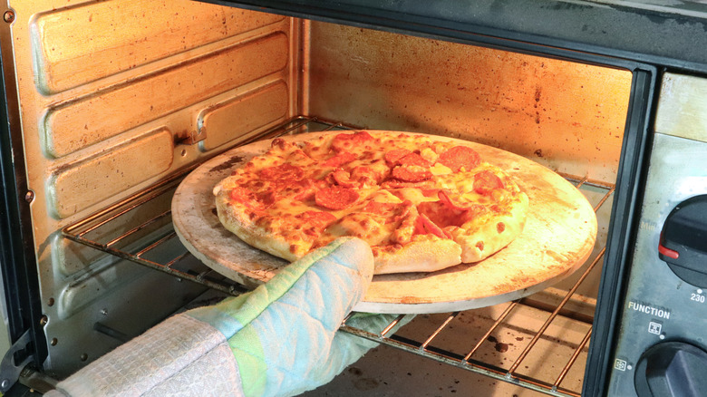 putting pizza in oven