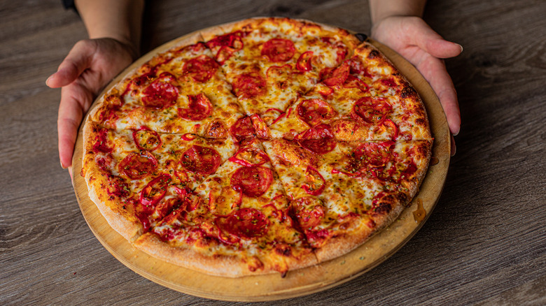 person holding large pizza