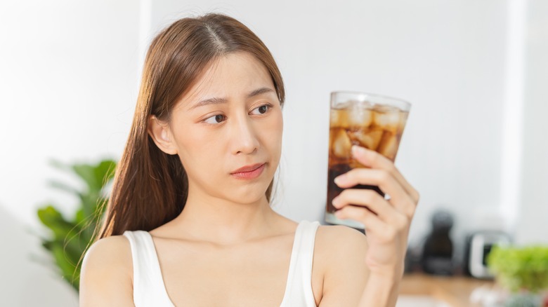 woman looking at soda glass