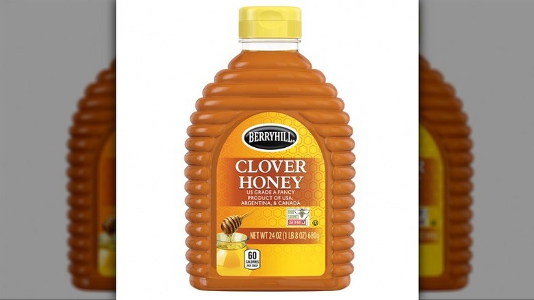 Berryhill clover honey in a ridged bottle with a yellow lid on white background.