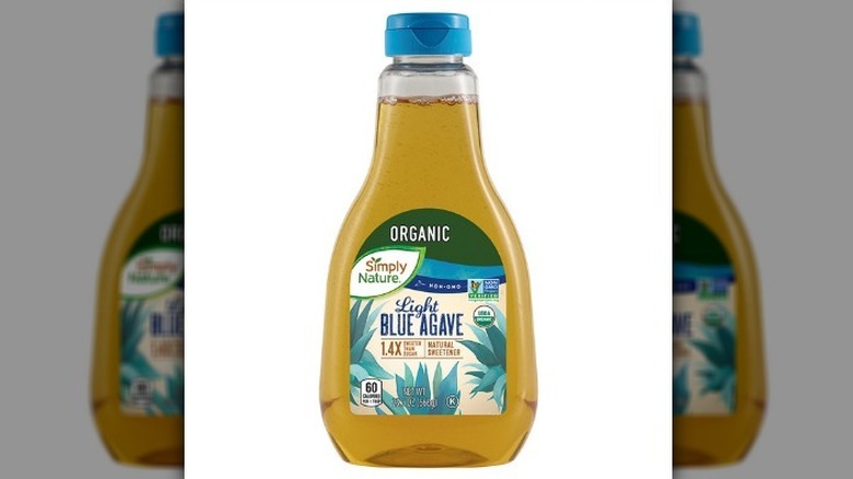 Light blue agave nectar in a clear plastic bottle with a blue lid on a white background.