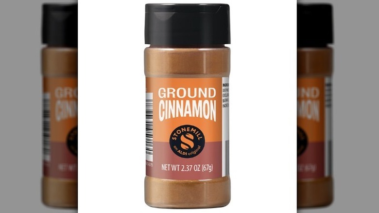 Ground cinnamon in a plastic bottle with a black lid on white background