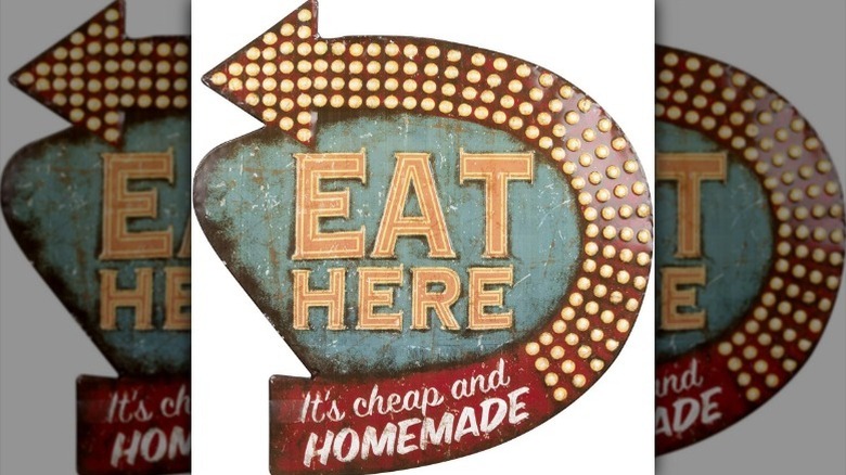 Metal "Eat Here" sign against white background.
