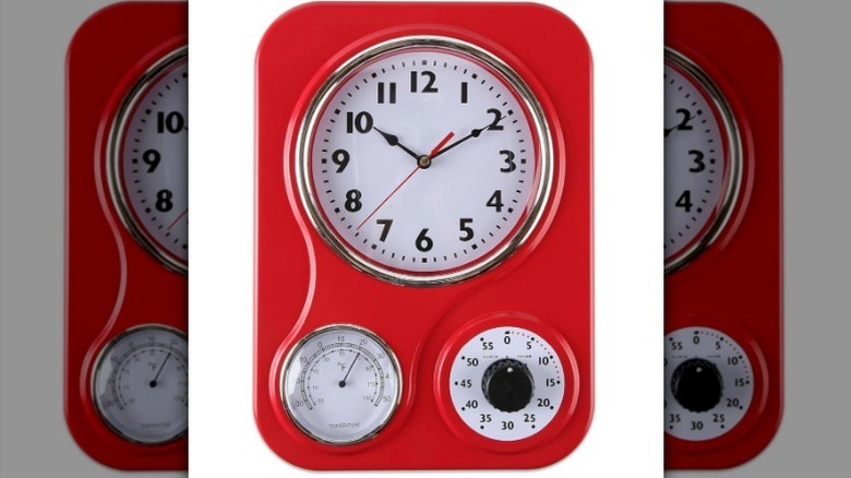 Red retro kitchen wall clock against white background.