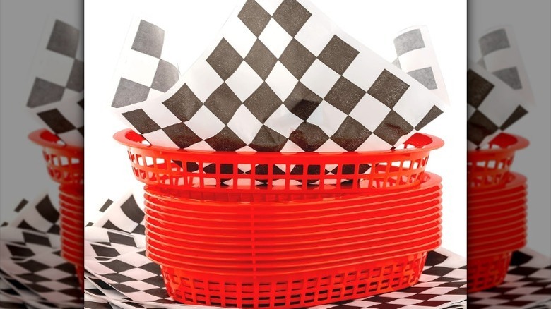 Stack of red baskets with black-and-white checkered liners against white background.