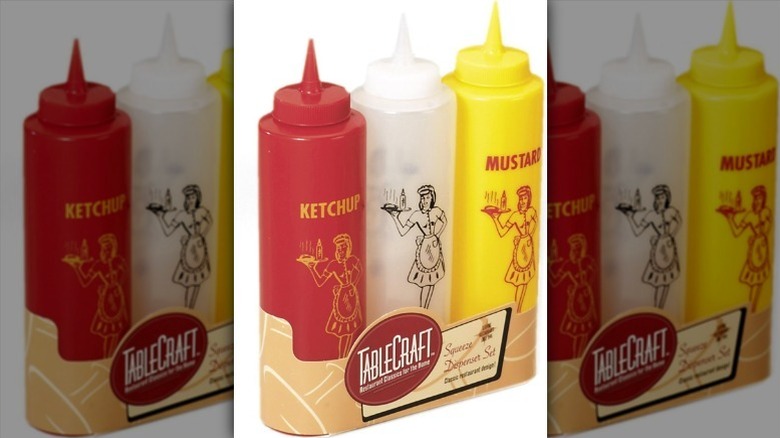Set of three condiment squeeze bottles against white background.