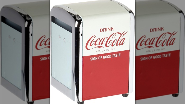 Coca-Cola napkin dispenser against white background.