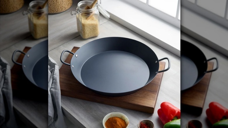 Paella pan on wood cutting board in kitchen