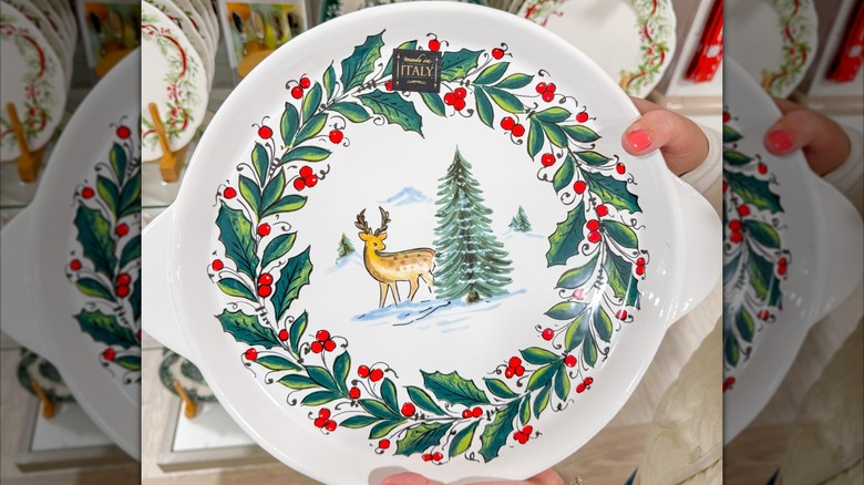 Person holding a serving platter with a deer, tree, and holly