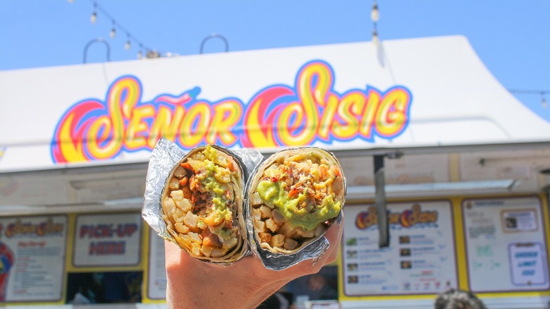 Person holding burrito in front of Señor Sisig food truck