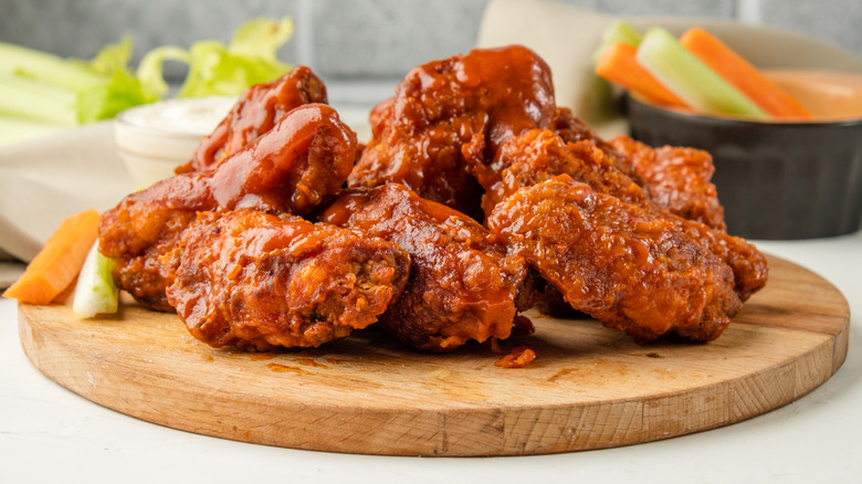 Wooden plate of buffalo wings smothered in sauce