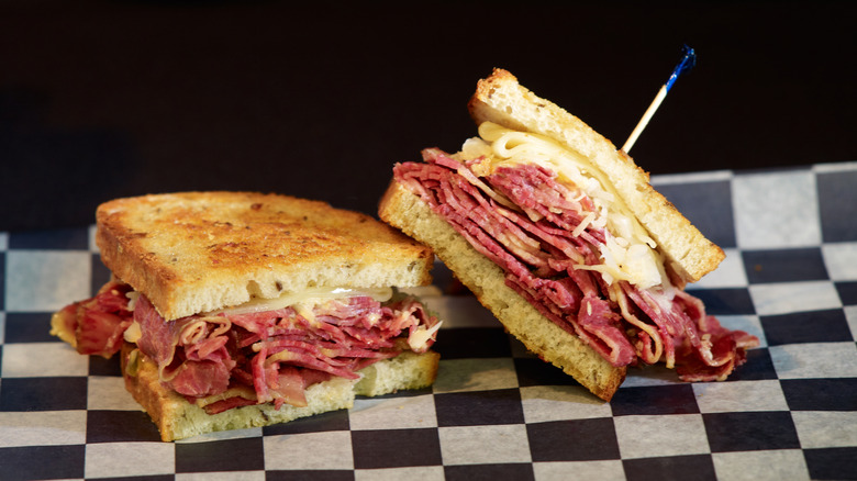 Loaded Reuben sandwich cut in half on black and white checkered paper