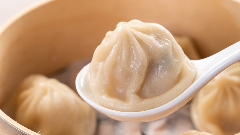 soup dumplings on spoon and in steamer