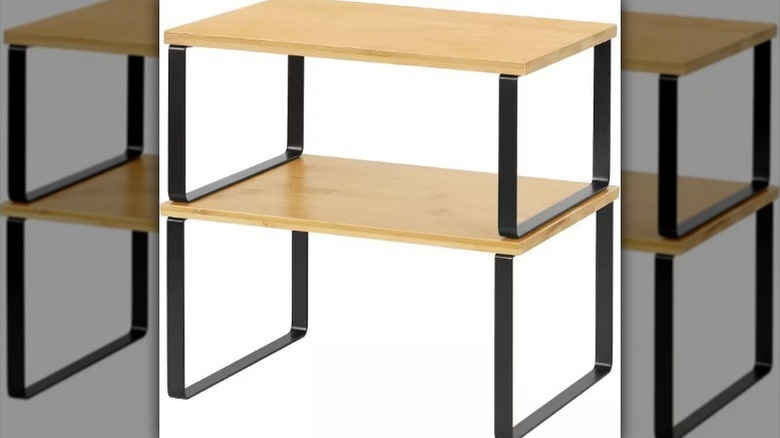 Two-tier bamboo shelf with black metal legs on white background.