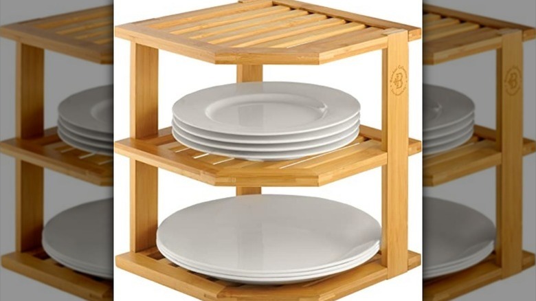 White plates on wooden corner shelf organizer against white background.