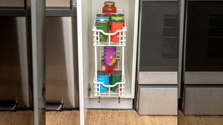 Jars and cans in narrow cabinet organizer inside kitchen cabinet.
