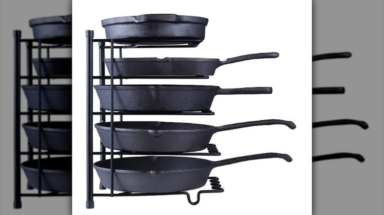 Cast iron skillets in black pan and lid organizer against white background.