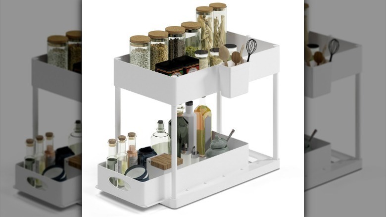 Under-sink storage organizer with pantry items on white background.