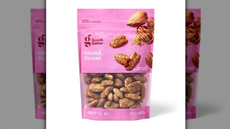 Glazed pecans in a pink bag on white background