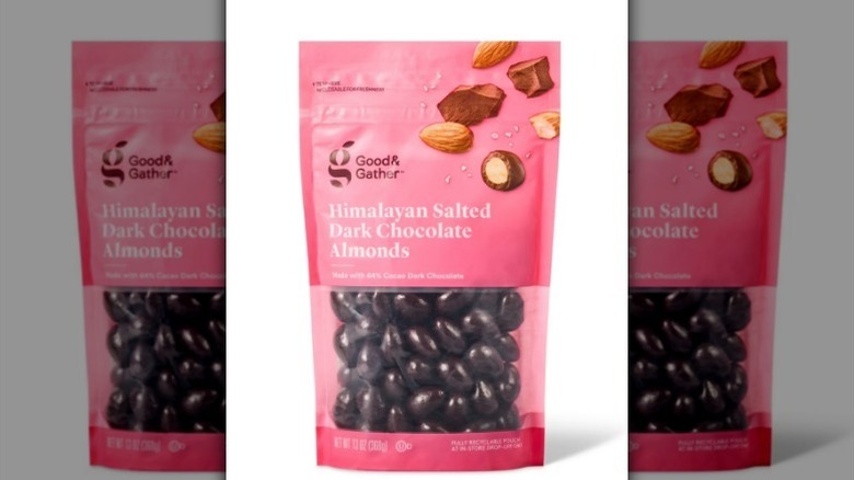 Chocolate almonds in a pink bag on white background