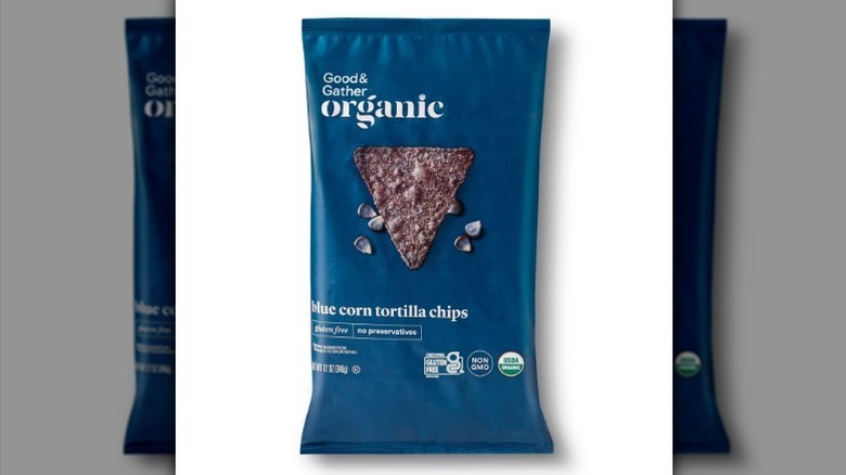 Blue corn tortilla chips in a blue bag on white background