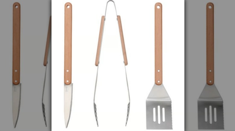 Barbecue set with knife, tongs, and spatula with light wood handles on white background