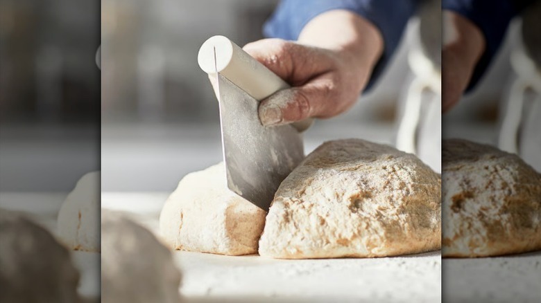 Hand holding dough cutter with dough