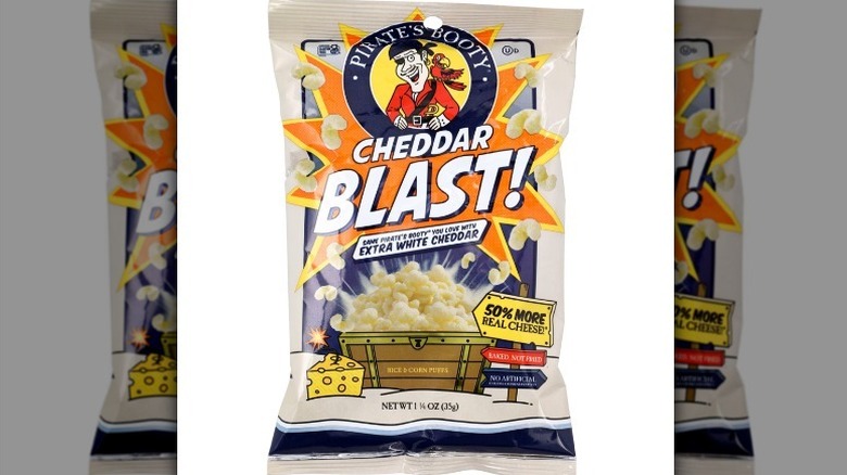 Cheddar Blast puffs with an orange, navy, and cream bag on white background