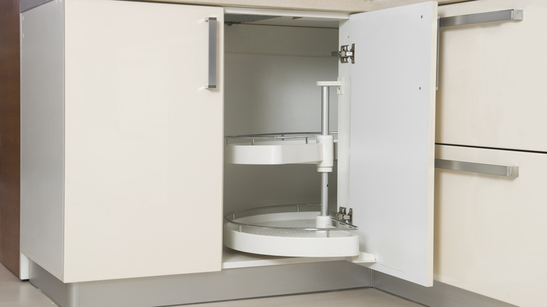 A corner kitchen cabinet with an open door showing a lazy Susan inside
