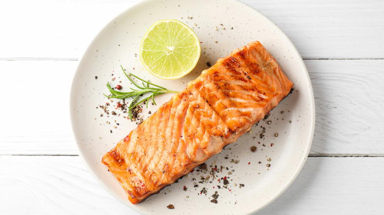A grilled salmon filet, skin down, with a round lemon slice