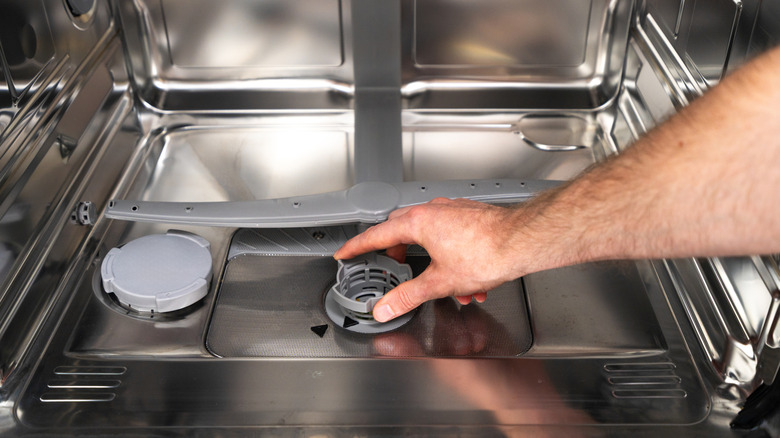 Hand adjusting a part inside a dishwasher