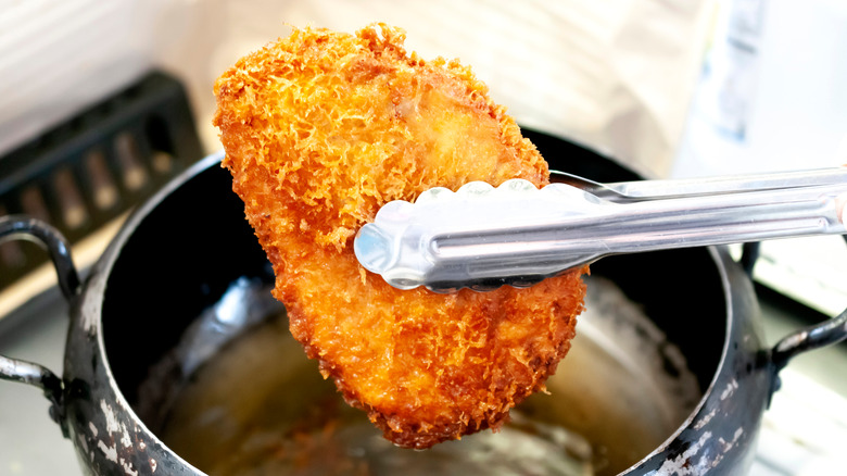 tongs grabbing piece of meat