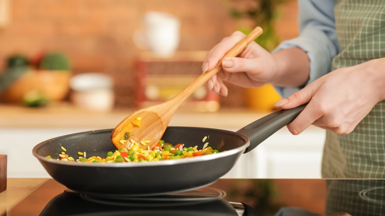 cook stirring pan with spoon