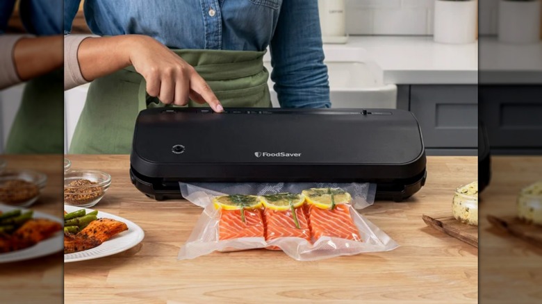Person using FoodSaver Preserve Vacuum Sealer Appliance with Bags and Marinate Container to preserve salmon