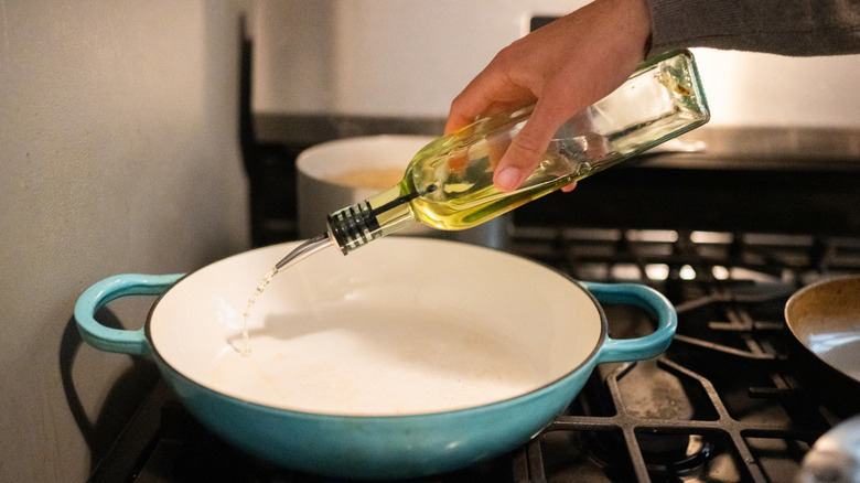 Hand pouring cooking oil into pan