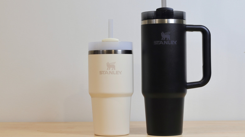 A smaller, white Stanley water bottle next to a larger black one
