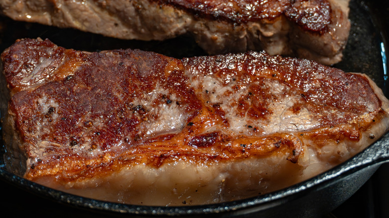 Close-up of the Maillard reaction on a New York strip in a cast iron skillet