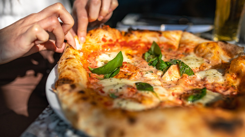 Woman pinching the dough on a pizza