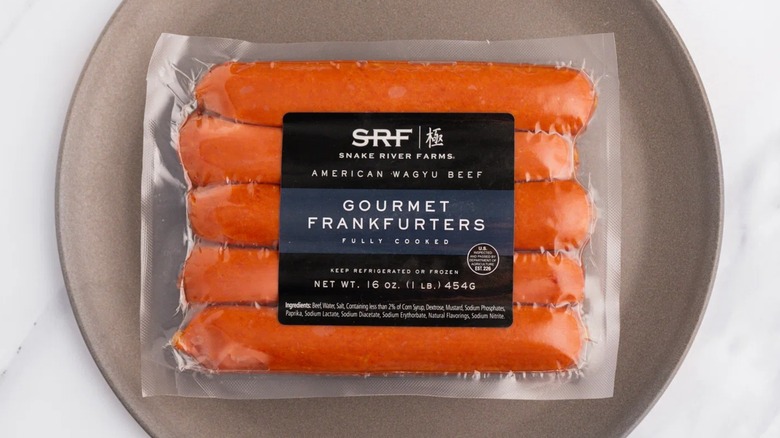 Snake River Farms American Wagyu Gourmet Frankfurters in their package sitting on a plate.