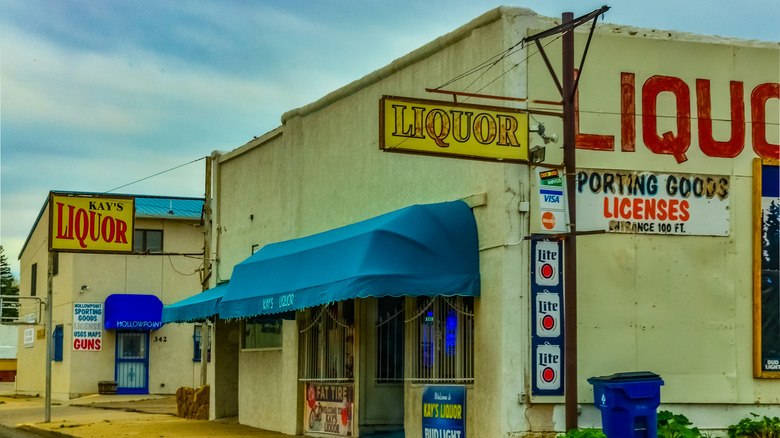 Two liquor stores with blue awnings side by side on a sunny day