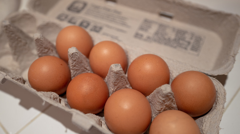 An open carton of brown eggs with nutrition information written on the inside of the carton