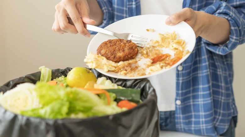 man scraping food into garbage