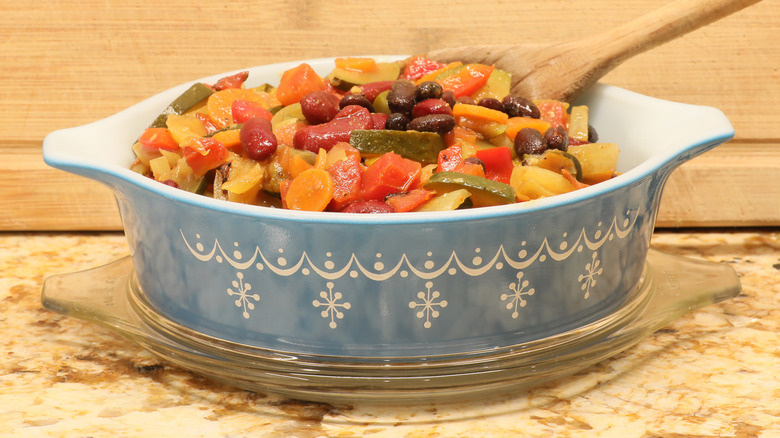 Vintage blue Pyrex oval casserole dish with mixed vegetables in it
