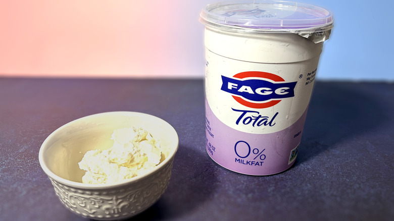 A tub of Fage Greek yogurt and a scoop in a white bowl