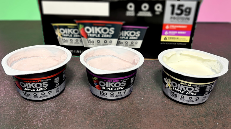 Three open containers of Oikos yogurt in front of box